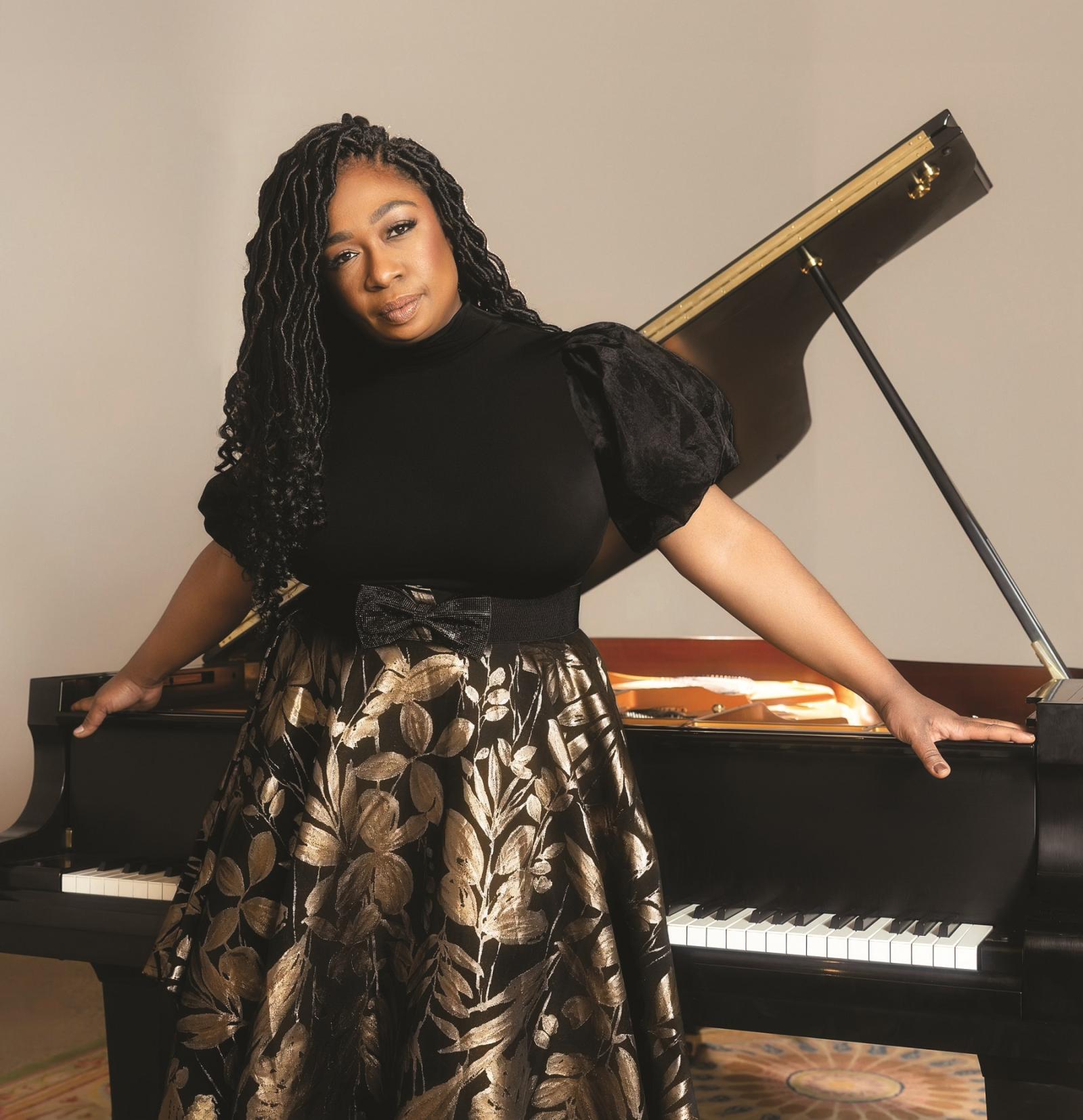 Michelle Cann poses for a photo in front of a piano.