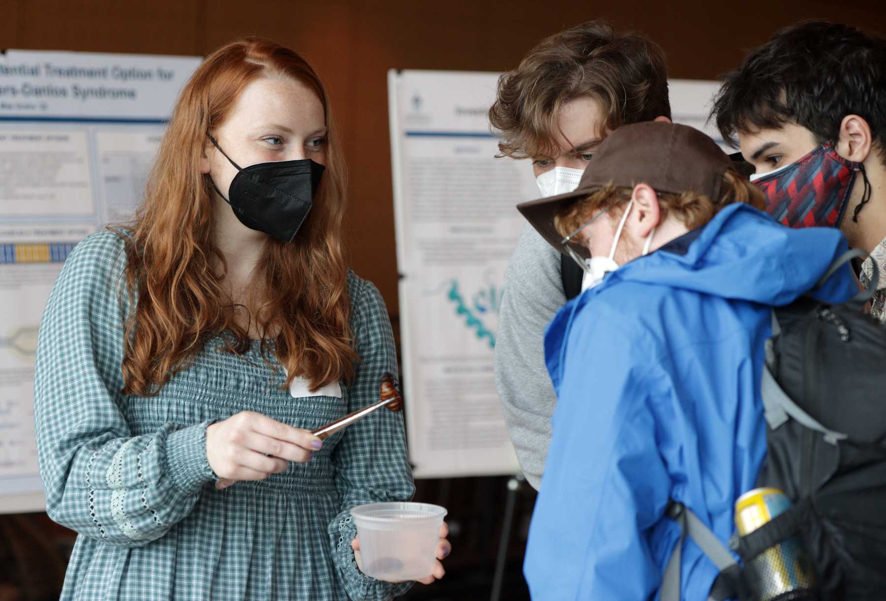 Anna White shows three students her research during Biofest.