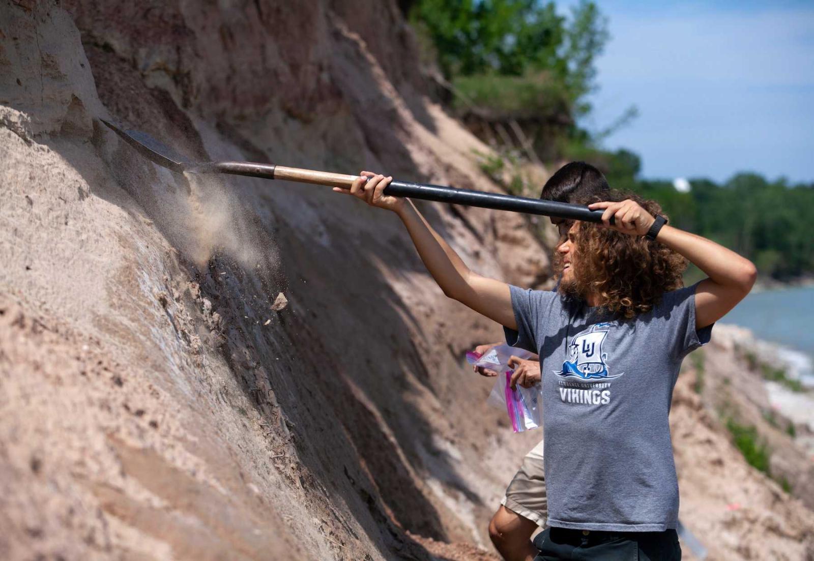 Students use shovels as they pull materials from a cliff during a research project near Two Rivers.