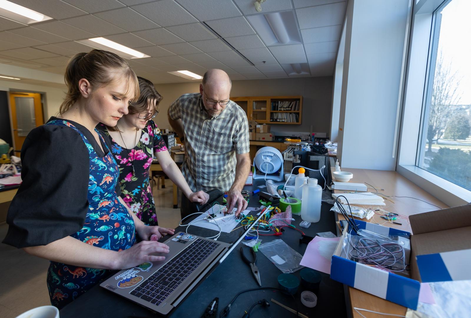 Geosciences professor Jeff Clark works with students Sydney Closson and Kat McClain in building spectrometers.
