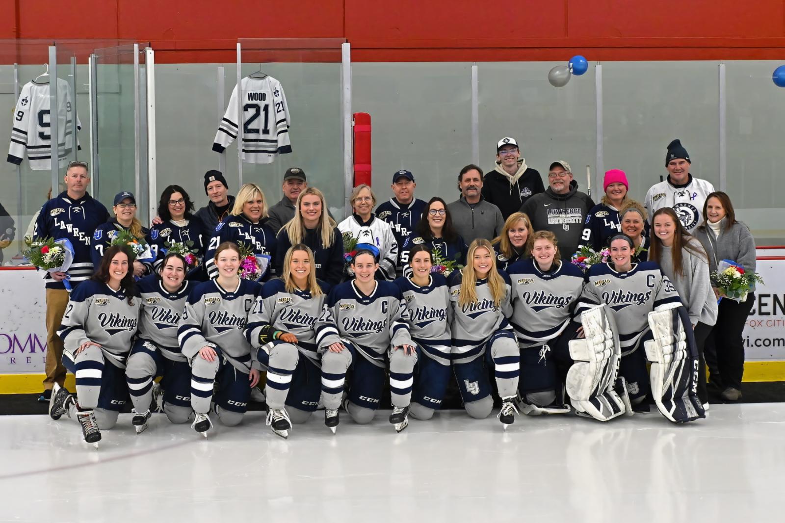 Nine seniors from the women's hockey team pose for a photo with family during Senior Day.