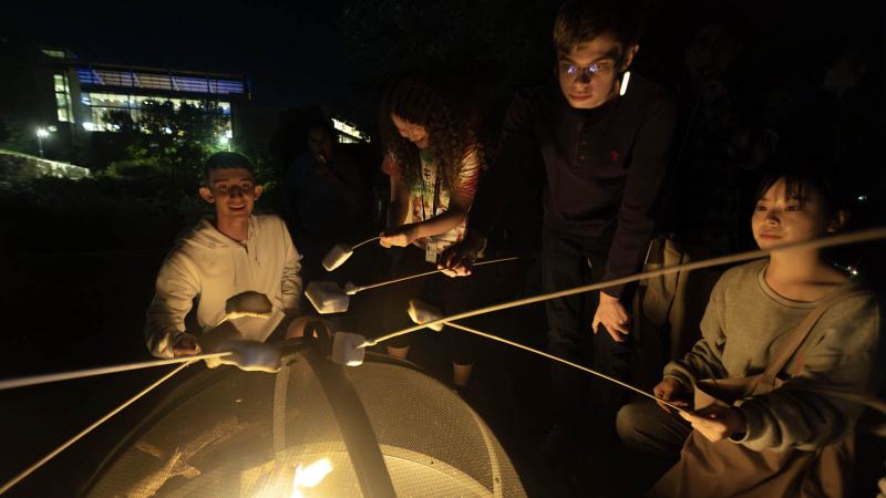 Students roasting marshmallows at night