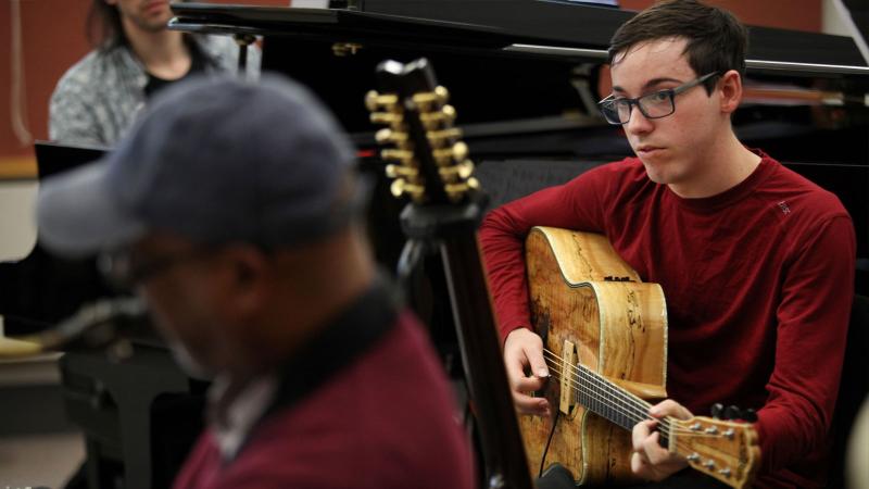 Student plays guitar during jazz rehearsal