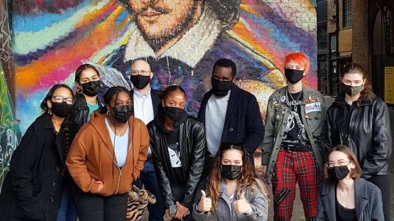 Masked students in front of Shakespeare mural