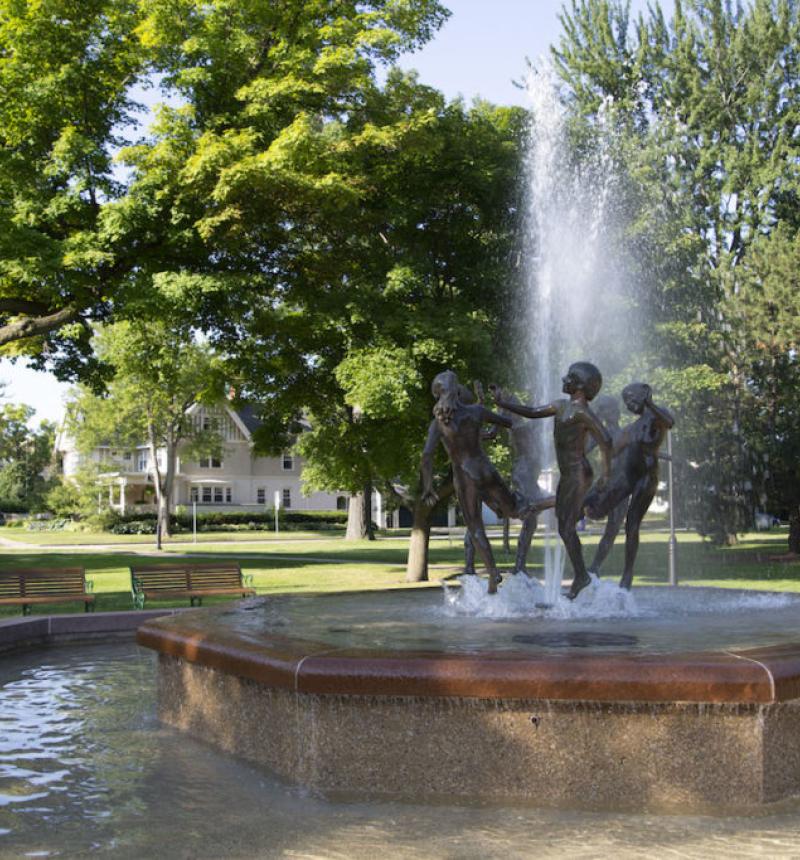 sculpture of kids playing in the middle of a fountain on a sunny day 