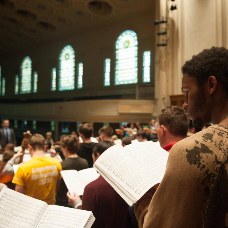 Singers with sheet music in hand during choir rehearsals in Memorial Chapel.