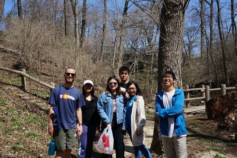 Volunteers in a park helping clean up trash on a midterm reading period service trip