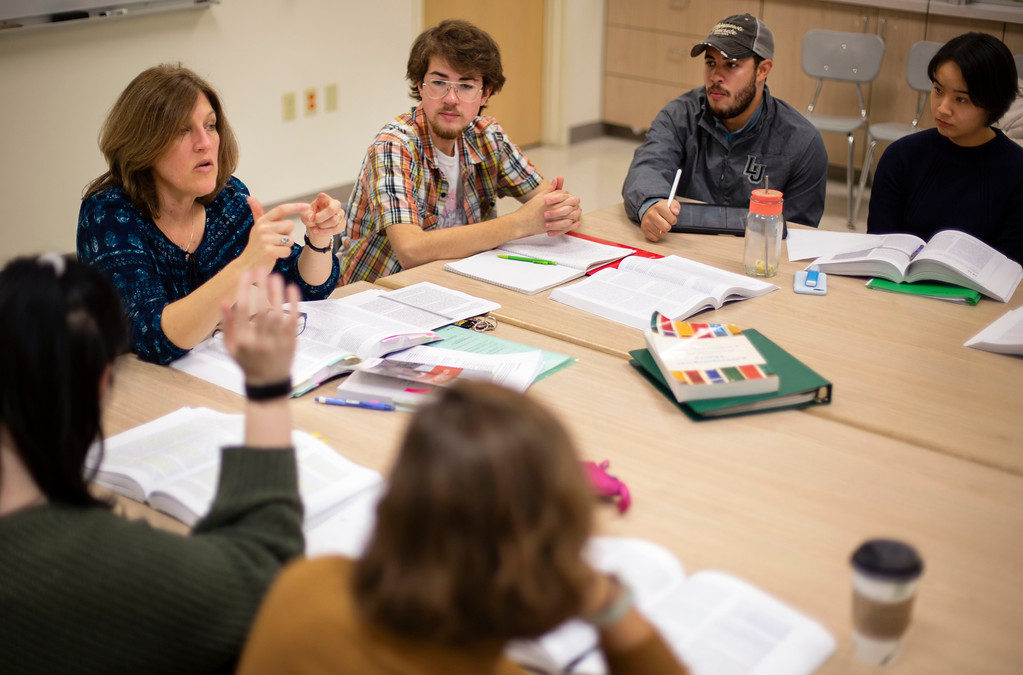 A professor sits around a table with a small class of students discussing biomedical anthropology.