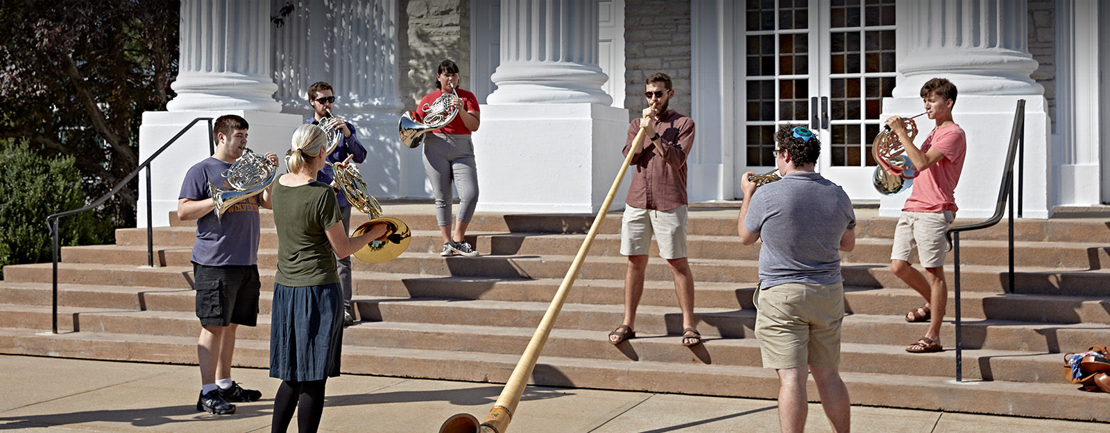 A group of students are performing on the steps of Memorial Chapel.