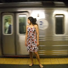 Leila Ramagopal Pertl standing in front of a moving subway train looking over her shoulder