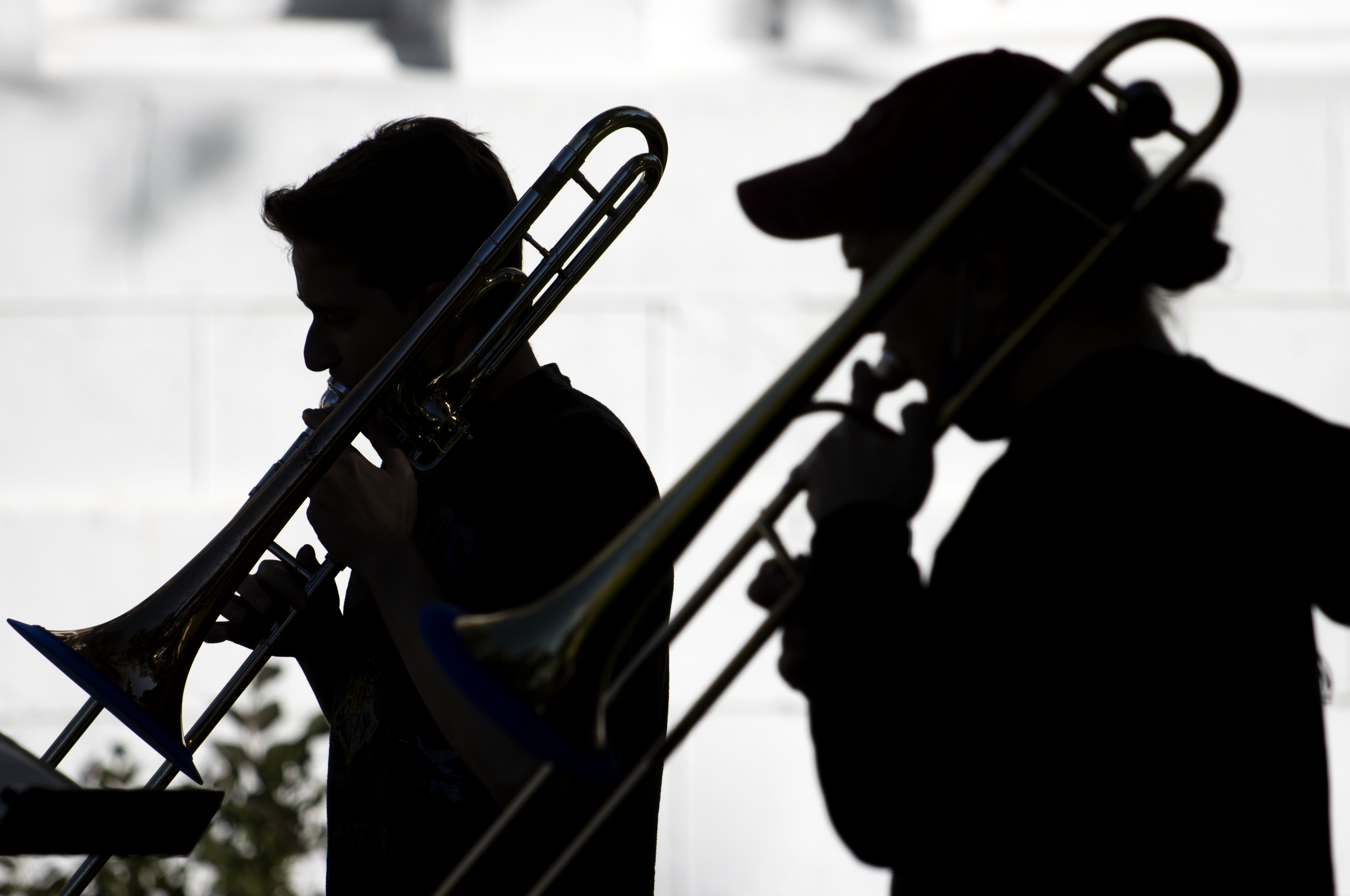 two students practicing trombone outdoors for jazz class