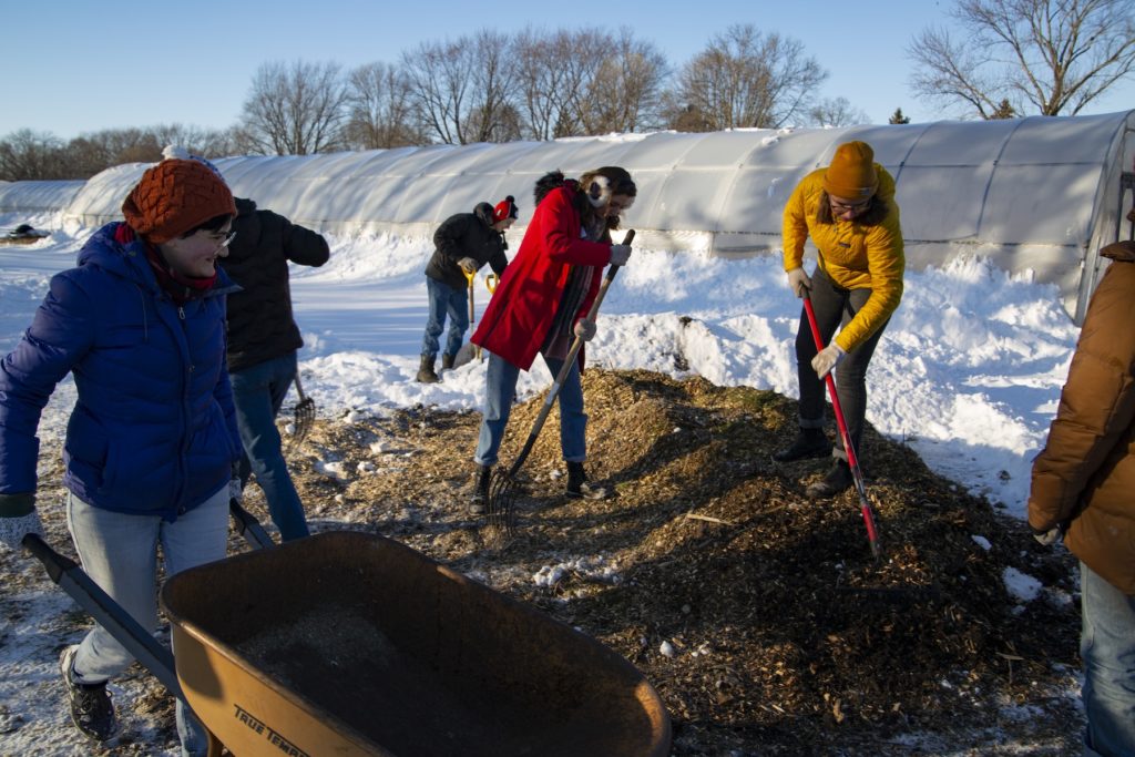 Students load mulch into a wheelbarrow at Riverview Gardens.