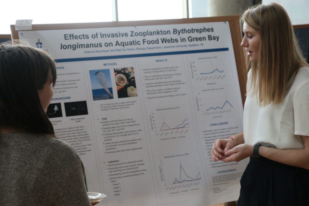 student looking at her poster while they present their research 