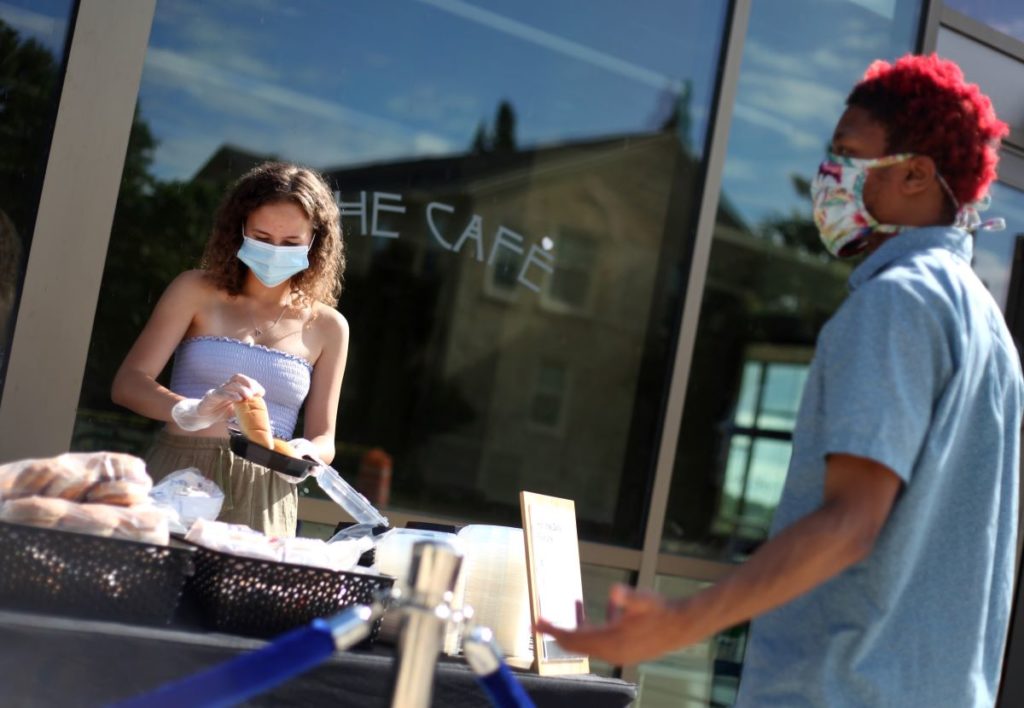 student serving food to another student outside The Cafe