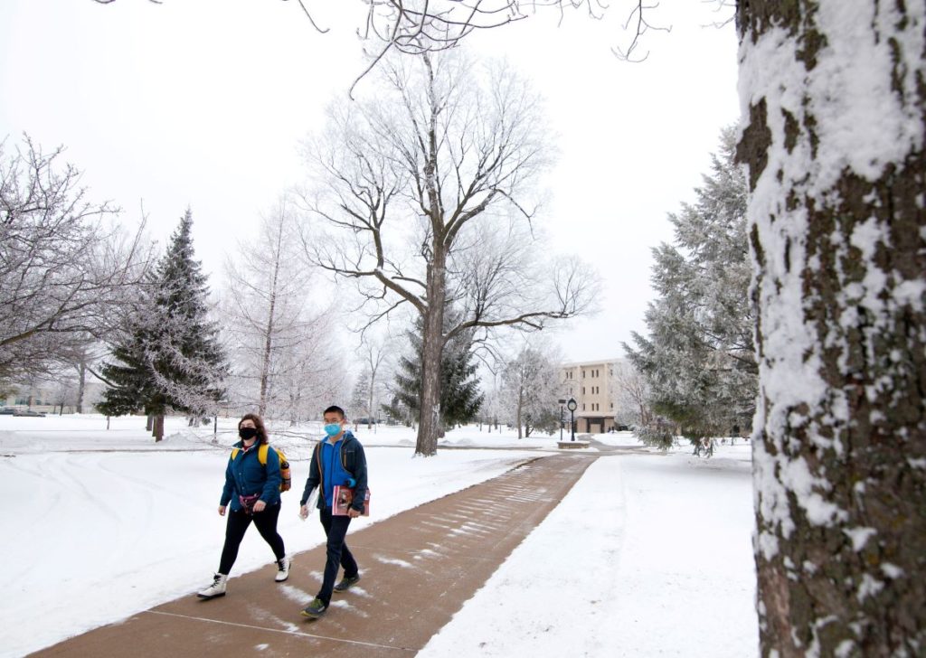 Two students walking across campus during snowy Winter 
