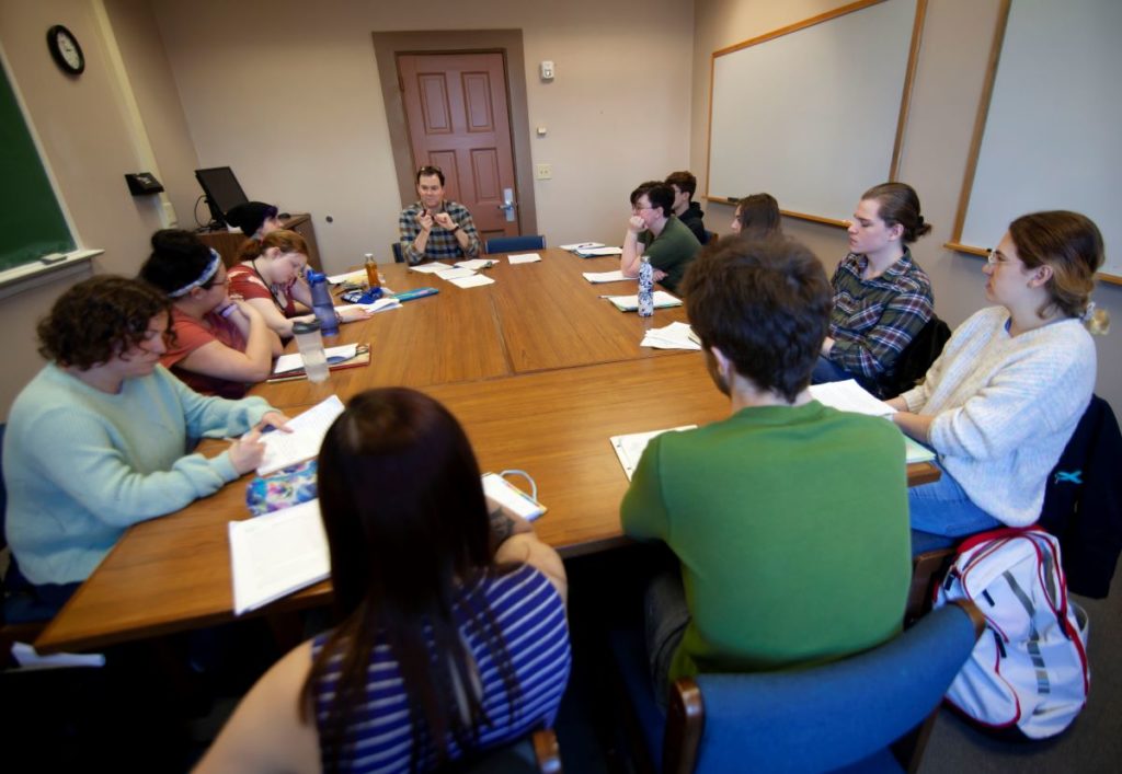 students sitting around a long table listening to the professor 