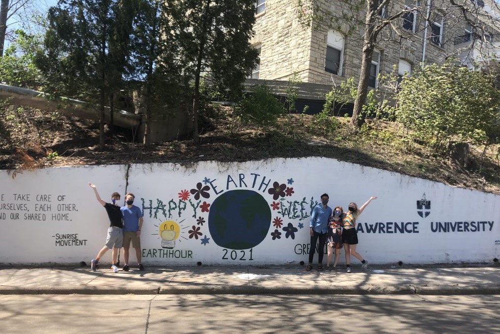 5 students taking a picture in front of the mural located in Drew St.