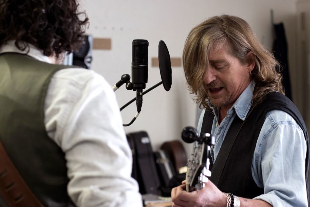 Close up of Rob Neilson singing and playing the guitar  