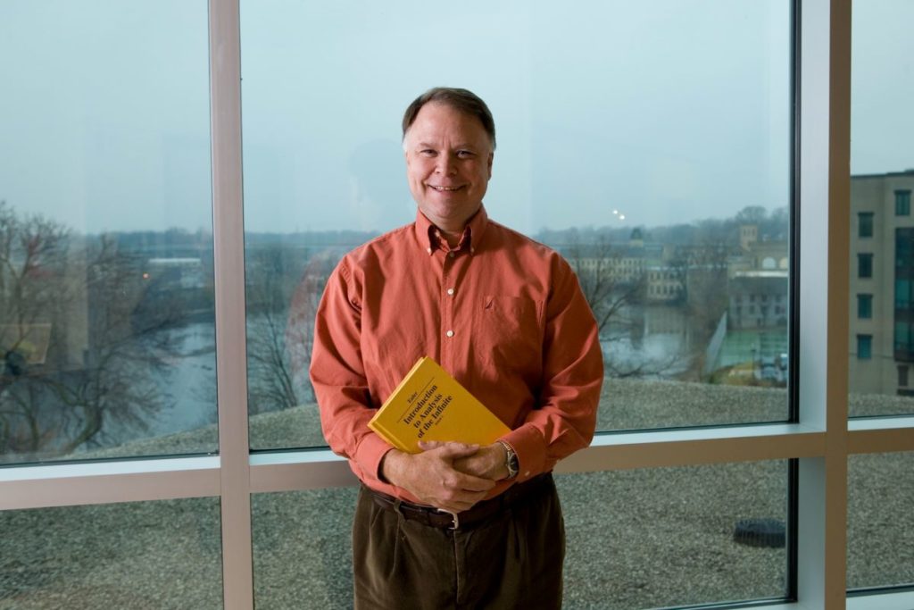 Alan Parks with a yellow book in his hands and the Fox river in the background