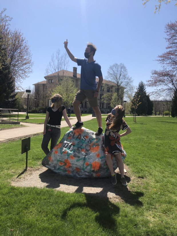 two students next to and one on top of the rock in Main Hall Green