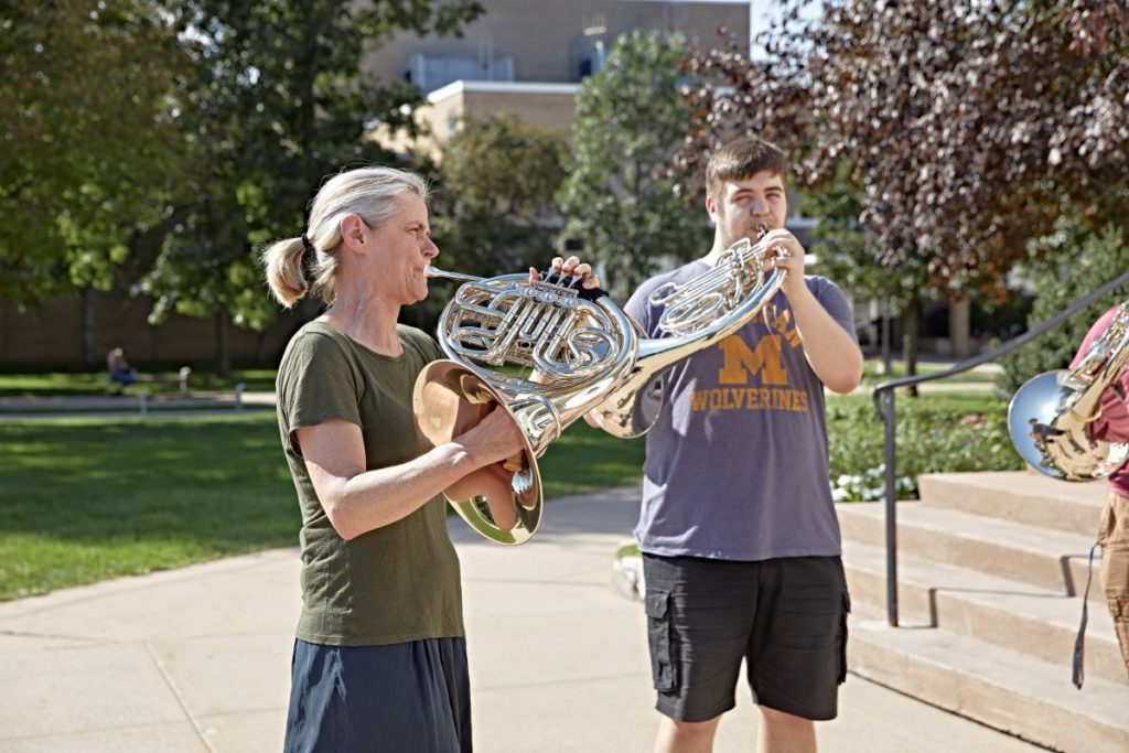 Professor Ellsworth playing the horn outside with her class