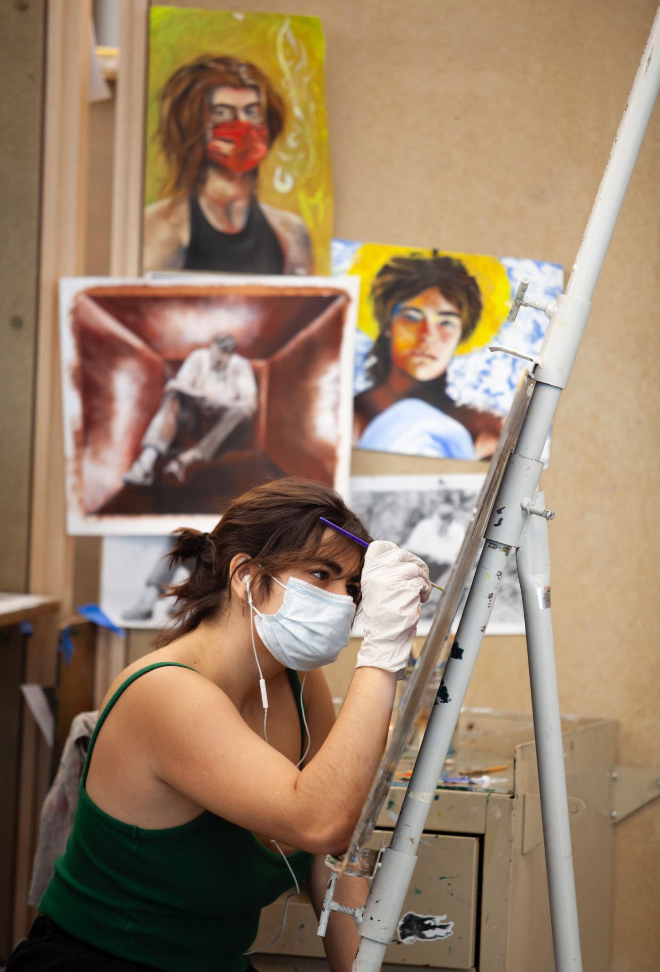 student painting at easel with completed painting in background