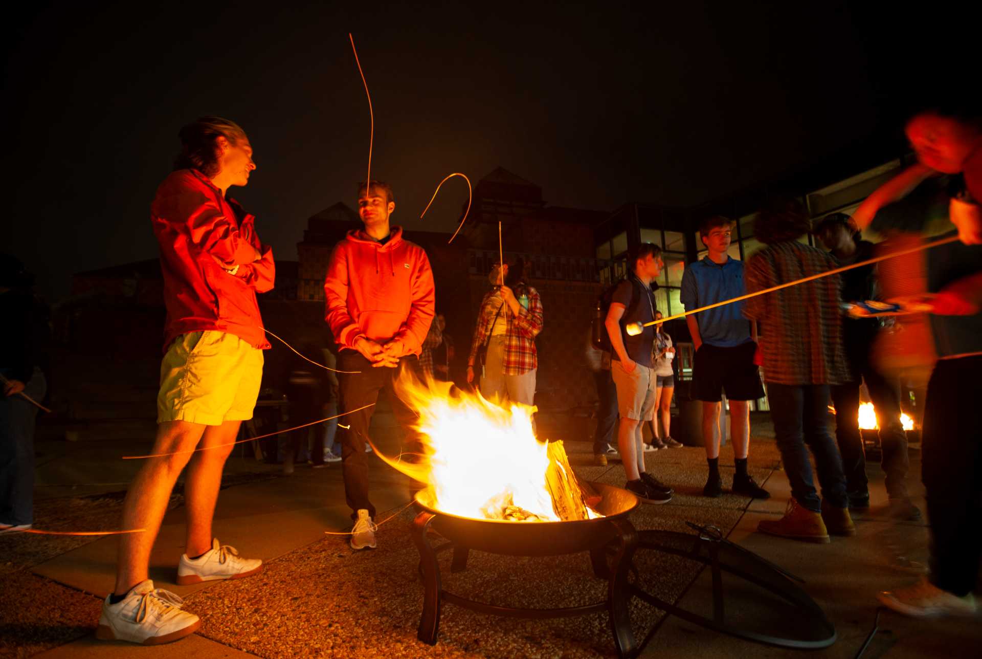 Matthew Pavlik, a sophomore, talks with Myles Luedecke, a junior, while standing around a fire during the Welcome Back Bon Fire in the Wriston Amphitheater.