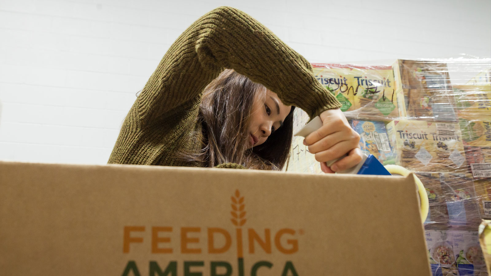 A Lawrence student packages supplies during a volunteer shift at Feeding America.