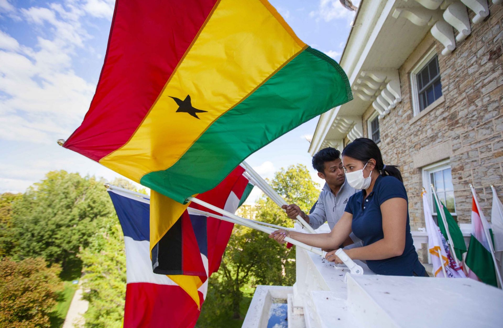 Two students hanging flags on Main Hall in preparation for the President's Welcome.