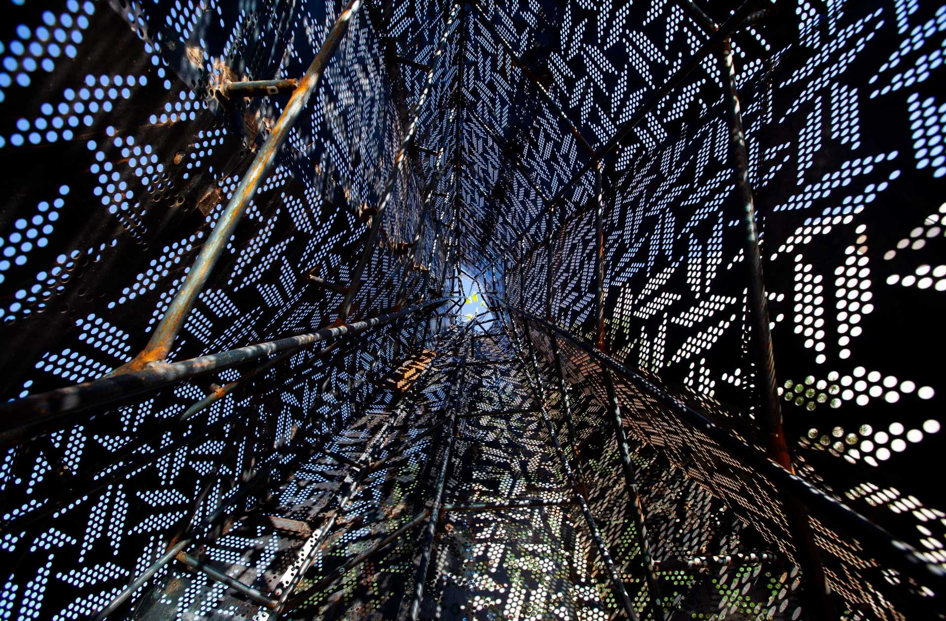 A cone of overlapping perforated steel plates viewed from the bottom up