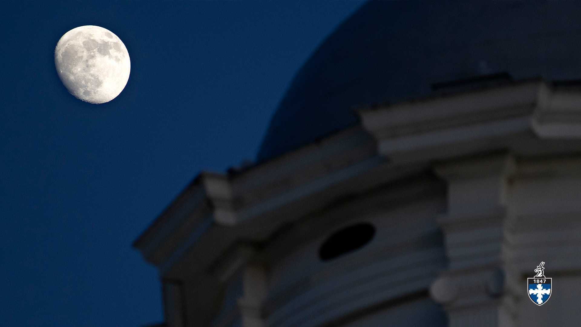 Close view of Main Hall's cupola with waning moon in background.