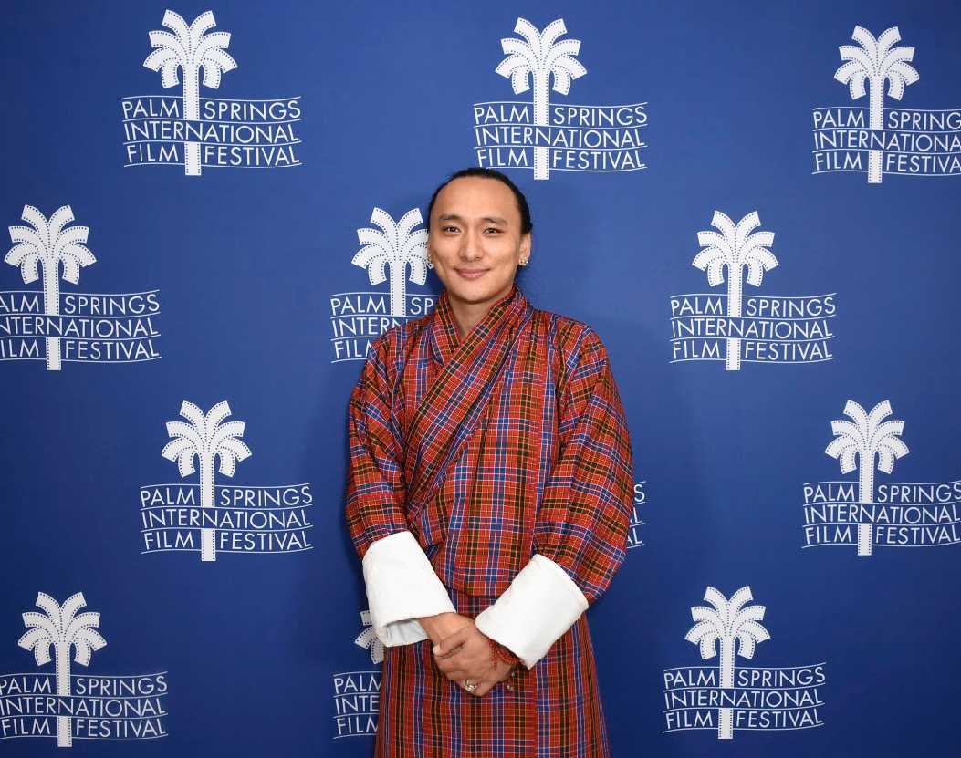 Pawo Choyning Dorji poses for a photo in front of signage for the Palm Springs International Film Festival.