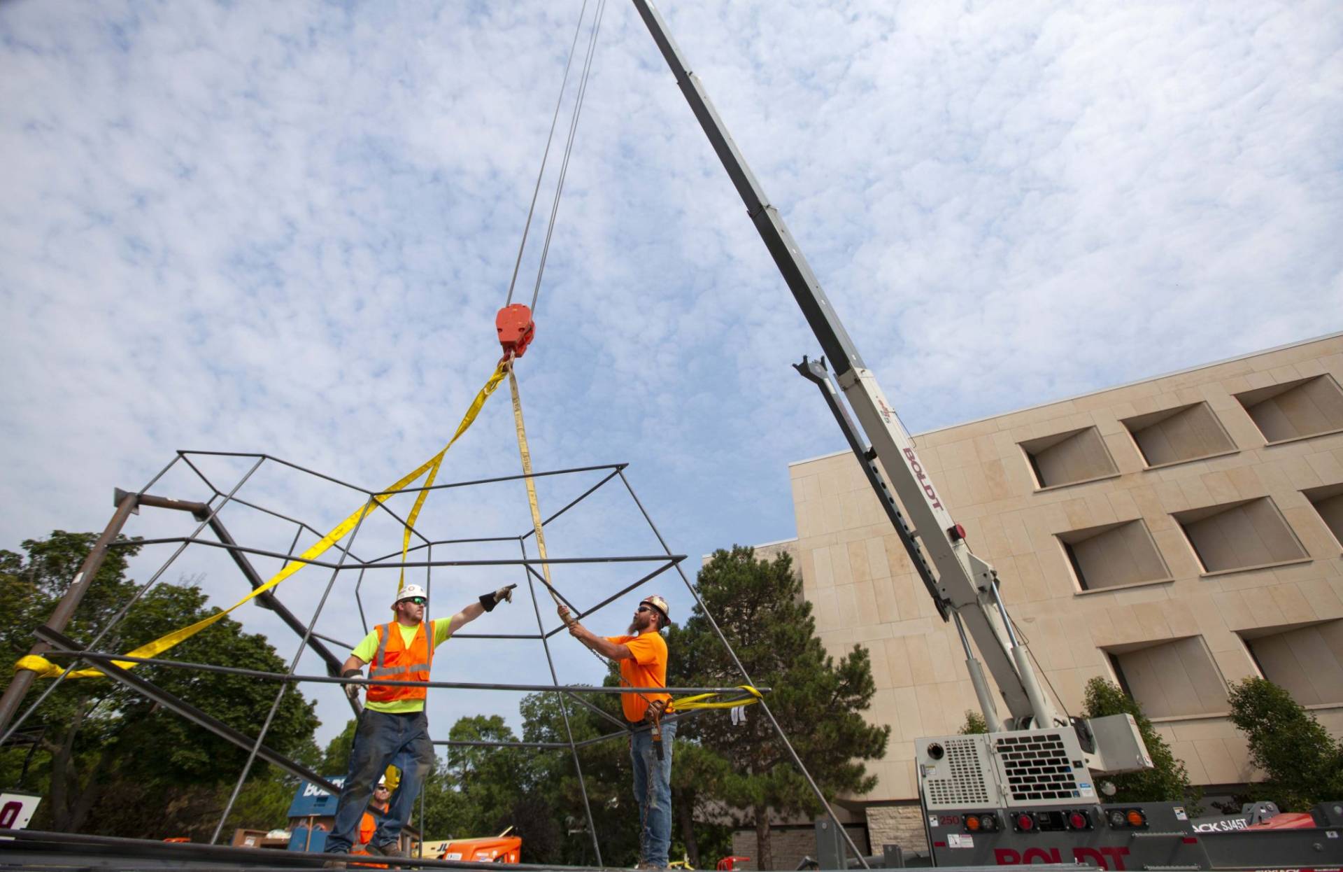 Two workers work with crane as they begin installing Otaeciah, the crane sculpture, next to the Mudd Library.