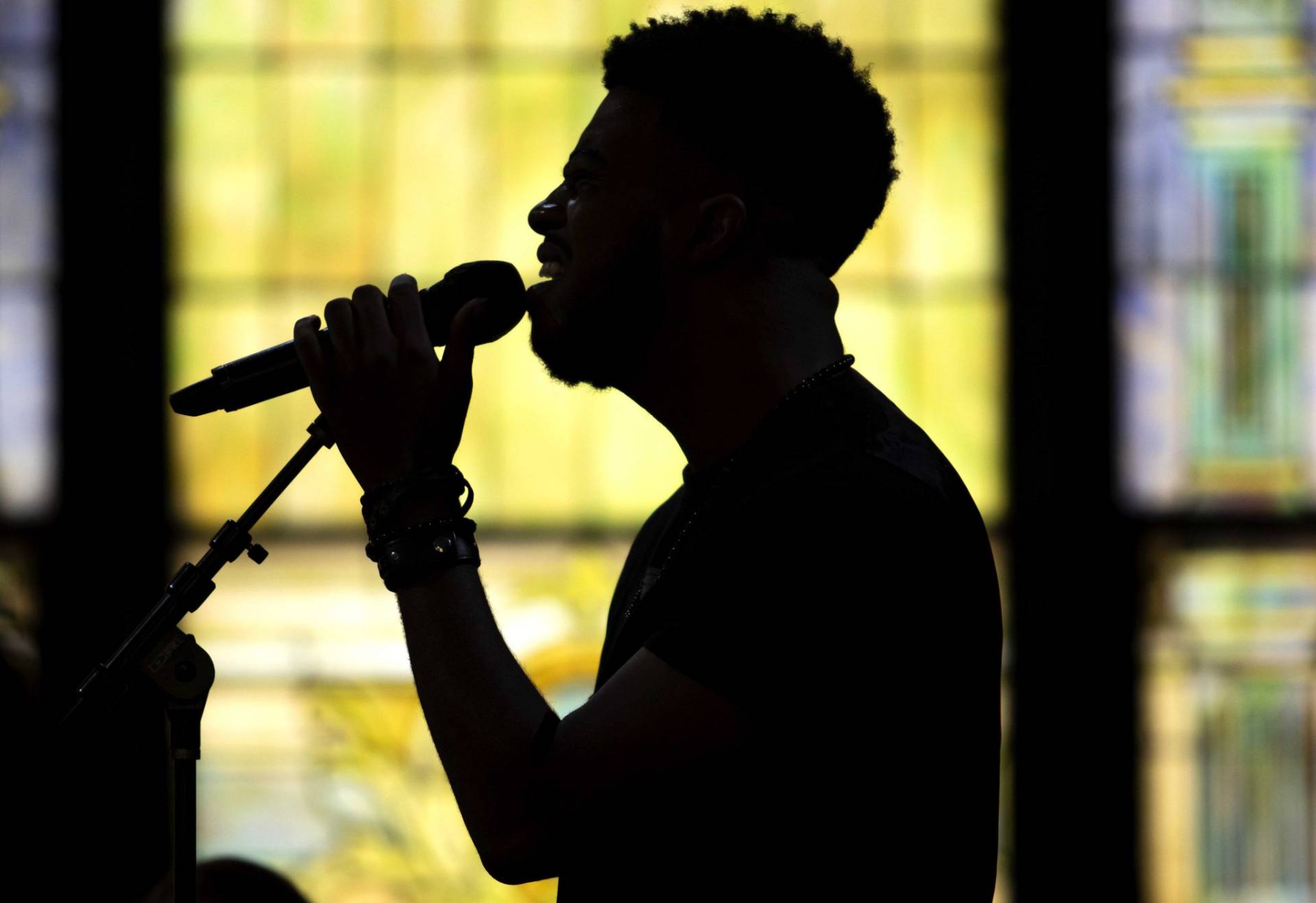 B. Lilly silhouetted against stained glass windows while singing into a microphone.