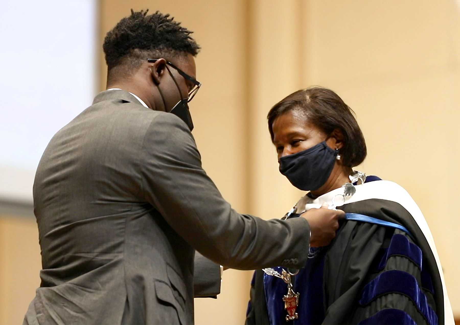 President Laurie Carter's son, Carter Walker Robinson, places the Chain of Office on his mother.