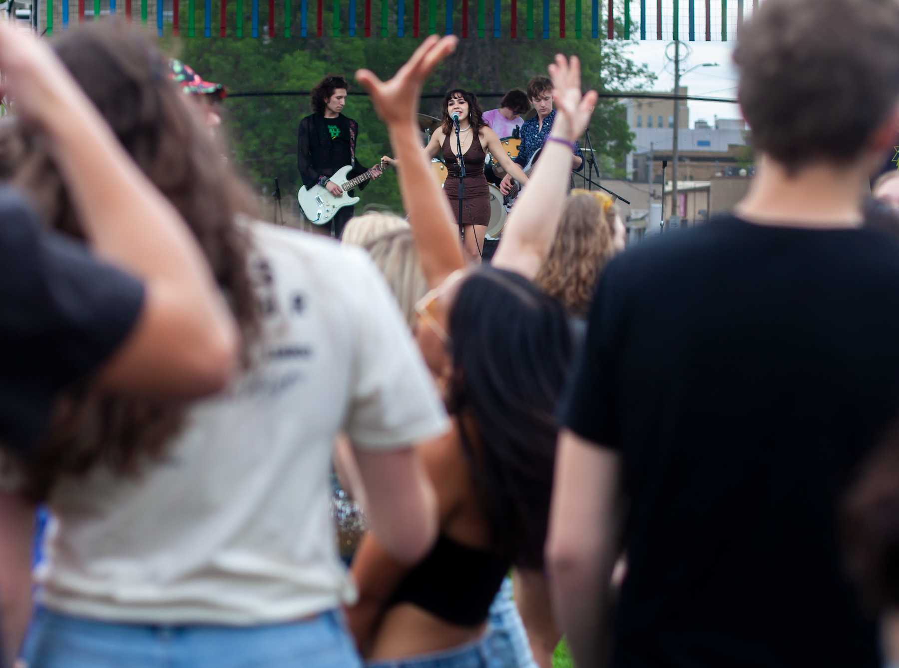 Audience members raise their hands as they watch a band on stage.