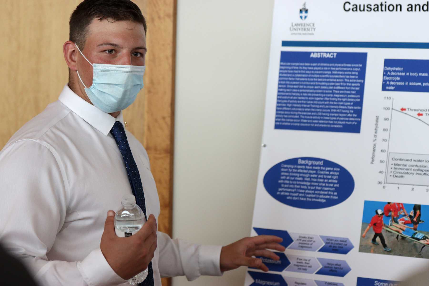 Zachary Burke explains his research in front of his board. 