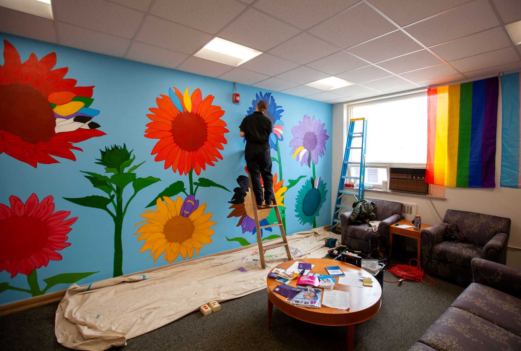 Cael Neary paints near the top of the mural as the project nears completion.