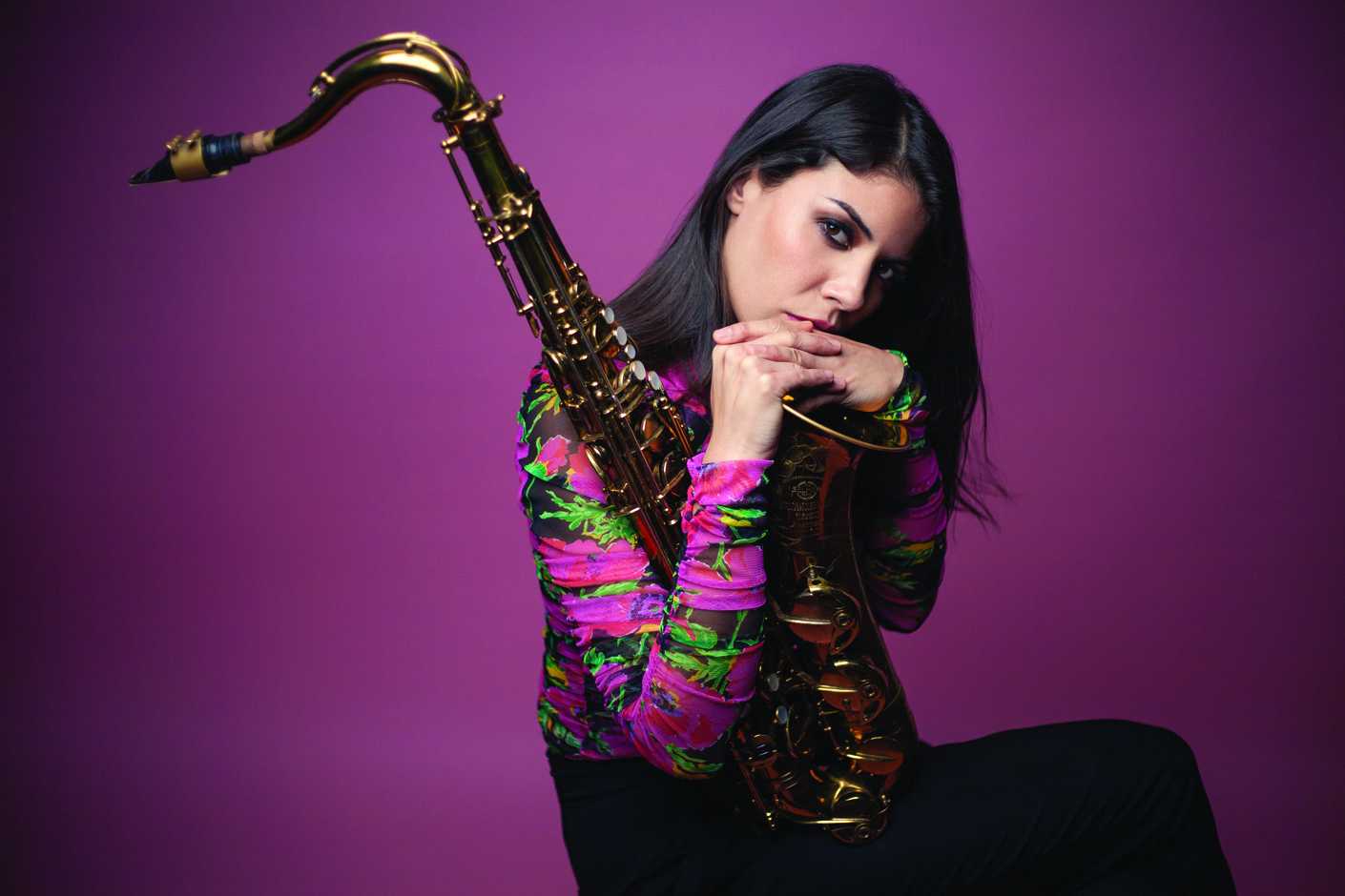 Portrait of Melissa Aldana as she holds a saxophone.