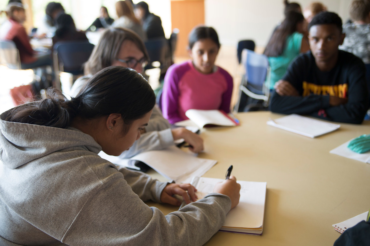 Summer Institute Participants sitting together at a round table, discussing and taking notes during class.