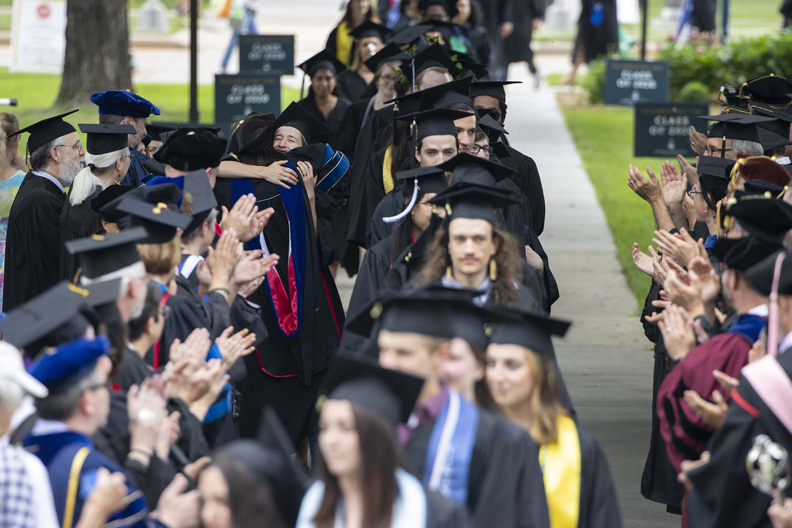 Megan Pickett, Associate Professor of Physics, hugs 2020 graduate Willa Dworschack during the Class of 2020 Commencement Celebration Ceremony’s procession. 