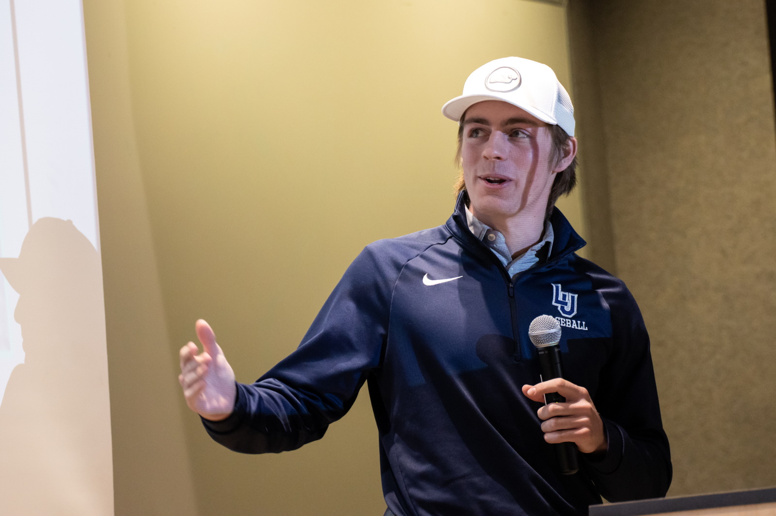 Henry Sipchen holds a microphone as he delivers his SchoolFinder pitch at Launch LU.