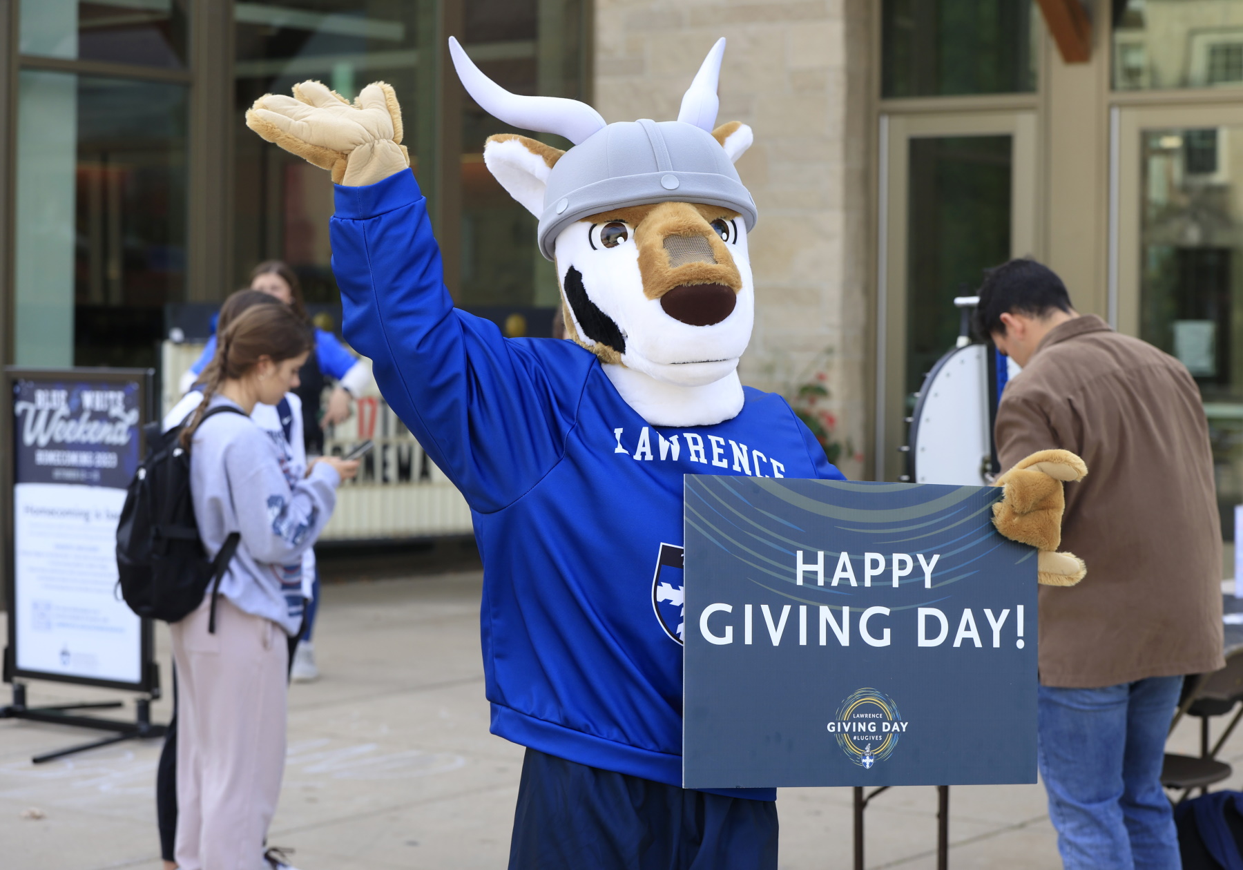 The mascot Blu waves as students take part in Giving Day games in front of Warch Campus Center.