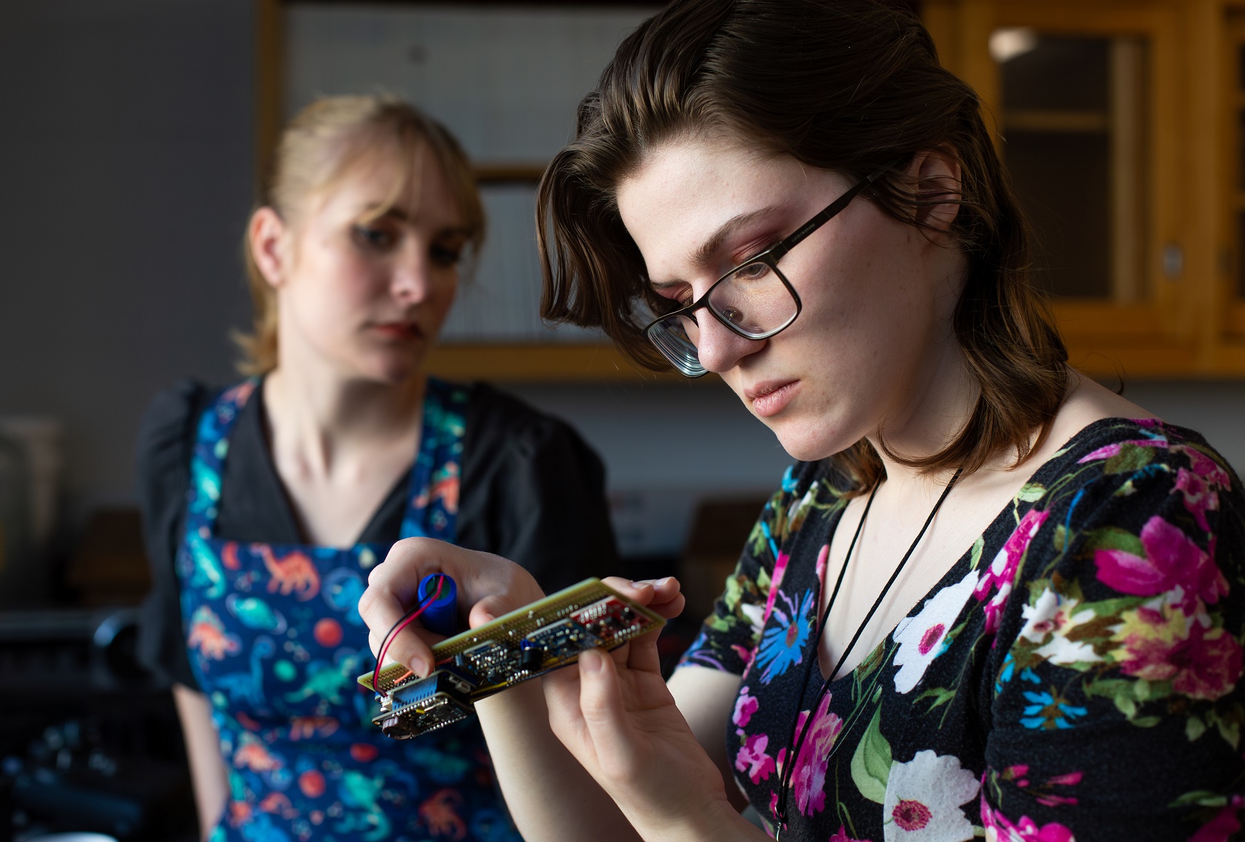 Kat McClain works on wiring in a spectrometer as Sydney Closson looks on.