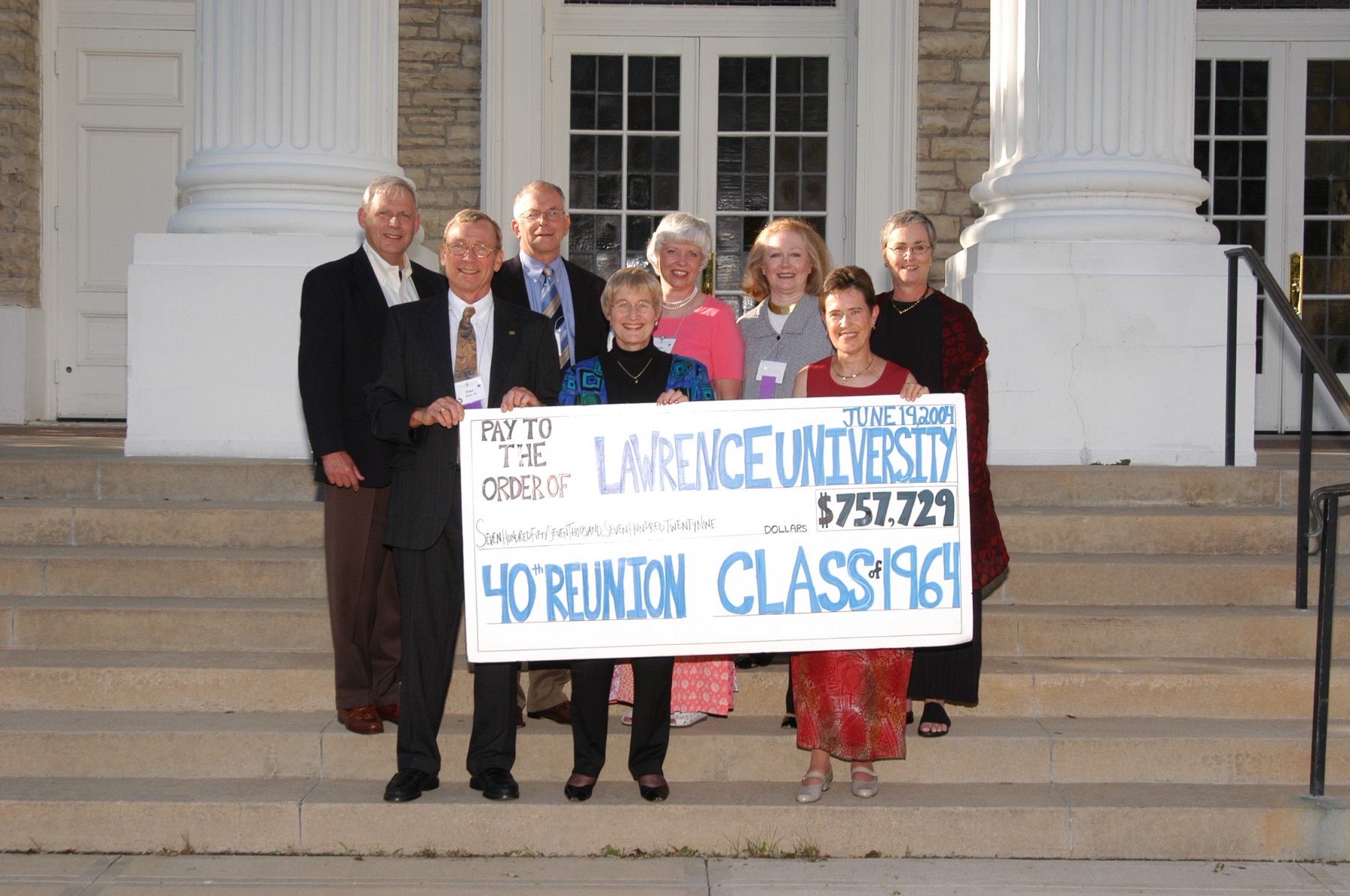 Bonnie Laird is seen front row to the right at a 2004 Reunion. Her and classmates are holding a sign showing the amount of the class's donation.