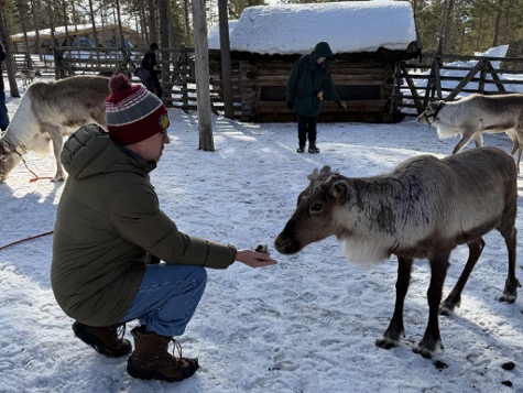 Bill Trost feeds reindeer moss to a reindeer during the Lawrence trip to Finland.
