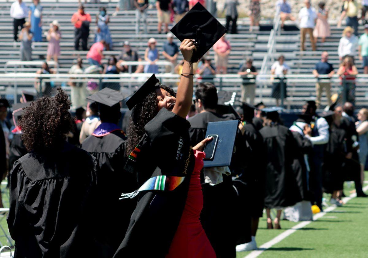 Graduates and a student showing their diploma during commencement 