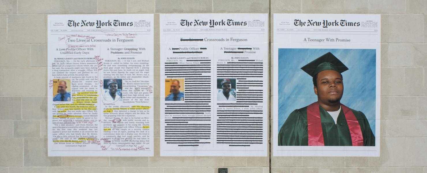 Three New York Times front pages, two with annotations and edits, pasted on a grey cinderblock wall