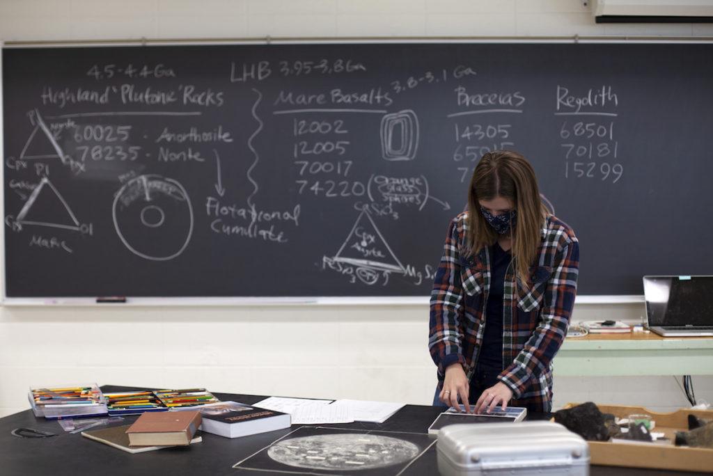 Student in front of a blackboard with equations 