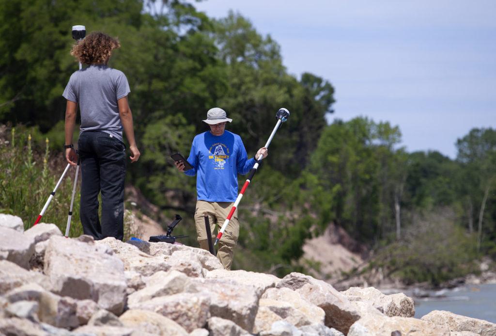 Student and professor standing on rocks near a creek 